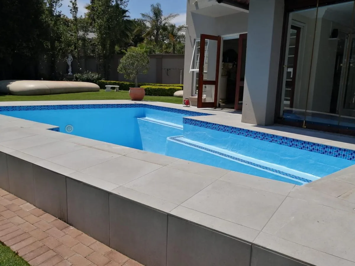 Finished pool with raised tiled entry steps and glass doors behind